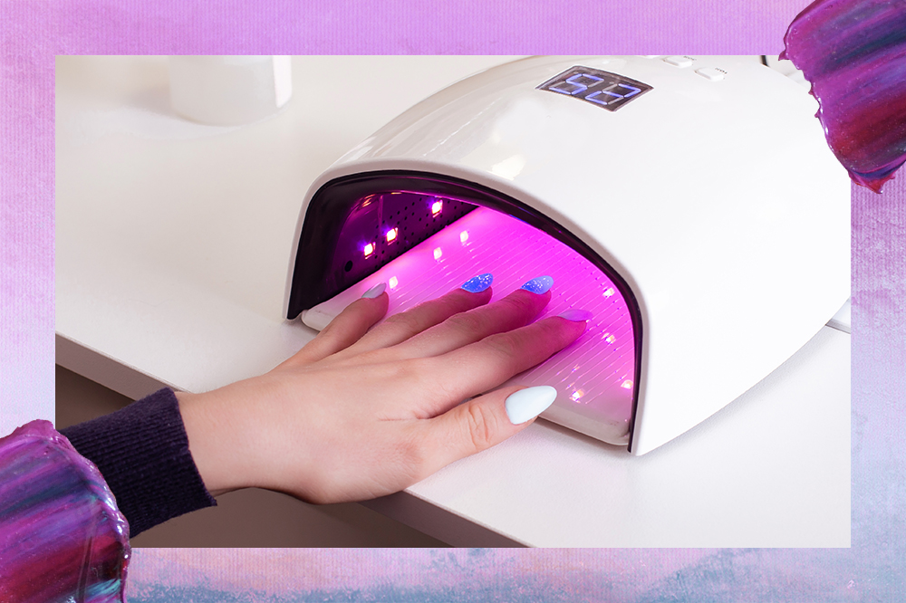 Foto de mão fazendo esmaltação em gel em cabine de luz de LED UV. Montagem tem fundo degradê lilás e azul