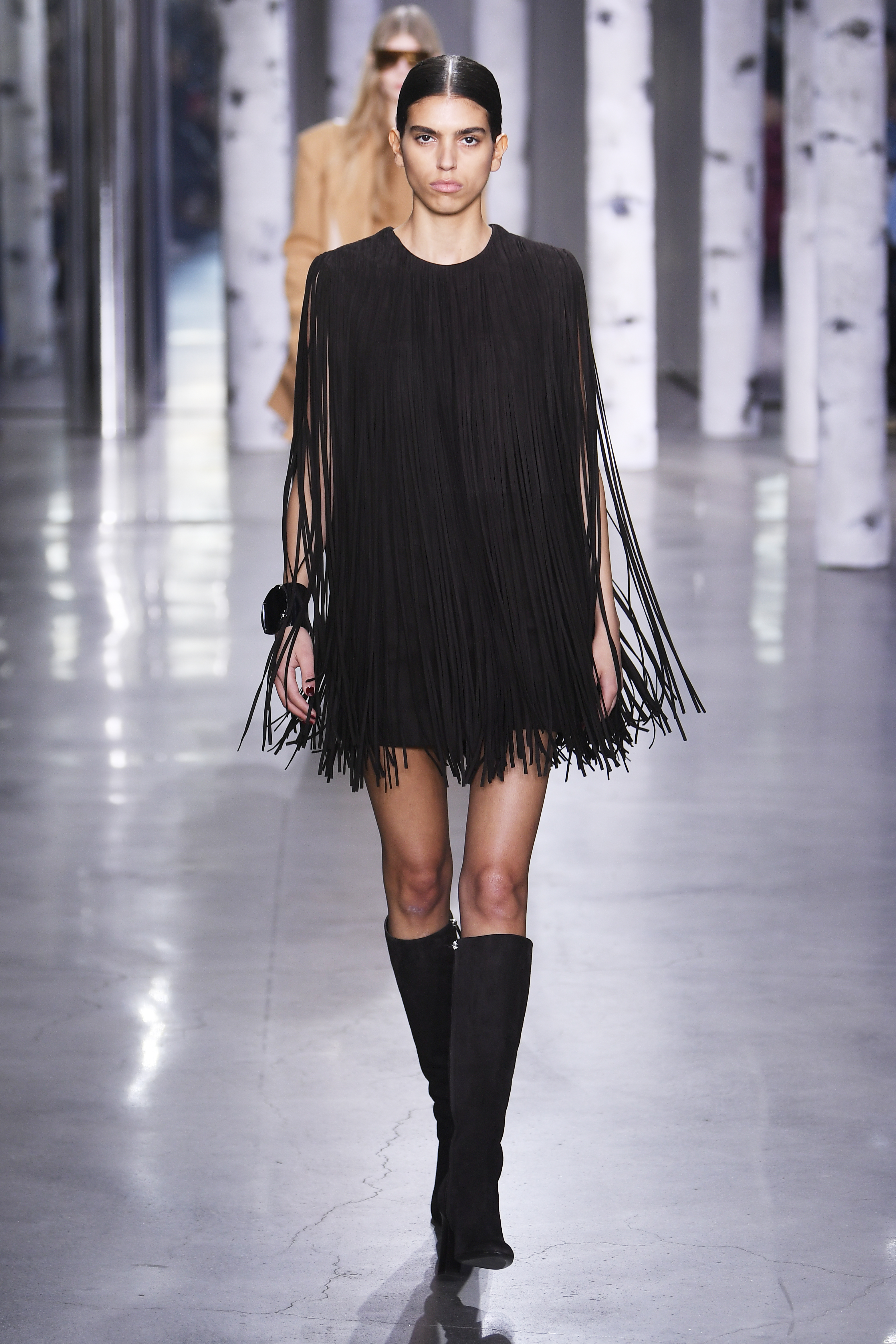 Desfile de outono-inverno 2023 da Michael Kors na semana de moda de Nova York. Modelo usando vestido preto de franjas e bota até o joelho