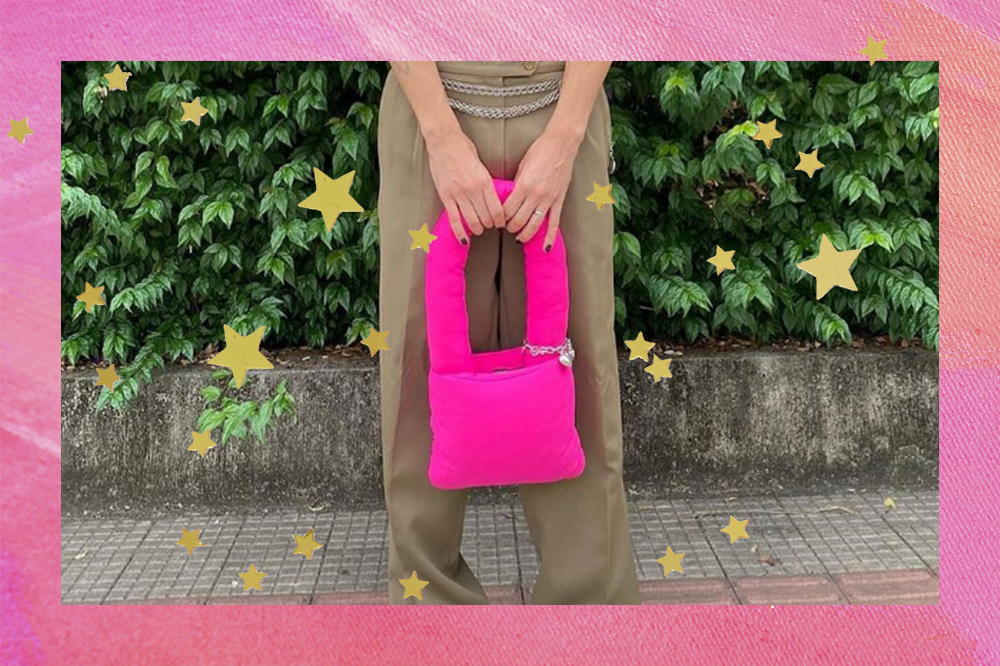 Montagem em fundo rosa com estrelinhas douradas com foto de pessoa usando calça marrom e segurando bolsa rosa puffer na frente do corpo com as duas mãos