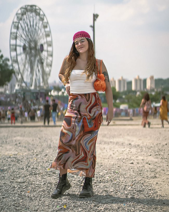 Foto de uma mulher no Lollapalooza 2023 com look com saia longa de estampa psicodélica, top branco e lenço na cabeça.