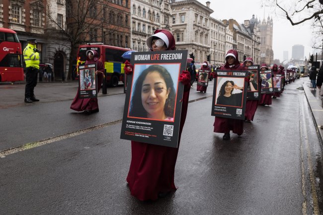 Protesto em Londres, no dia 8 de março de 2023. Vestidas de aias, ativistas seguram cartazes com fotos das mulheres mortas pela Polícia da Moralidade