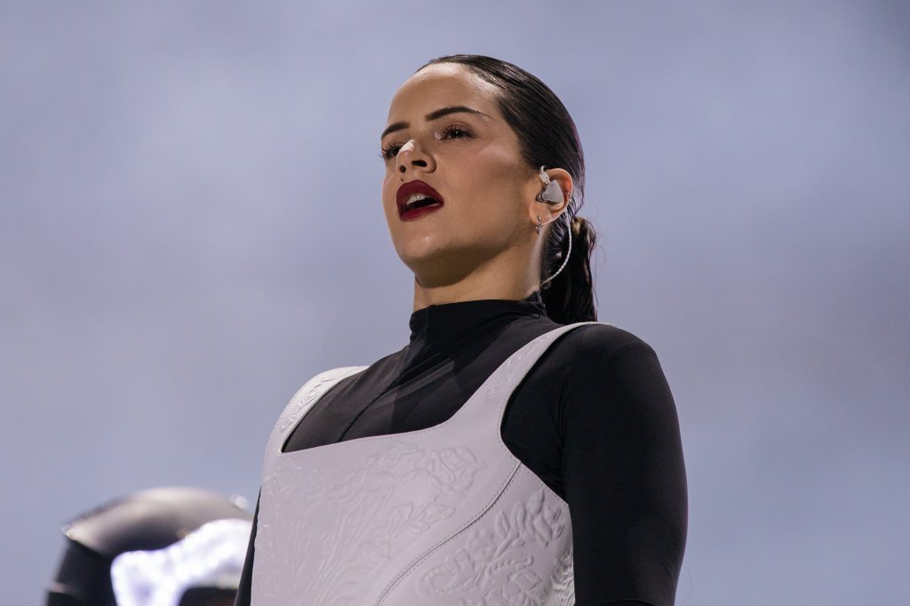 Rosalía no Lollapalooza Brasil 2023; ela usa um look preto e branco com batom vermelho e cabelo preso; a cantora está no palco performando com expressão neutra