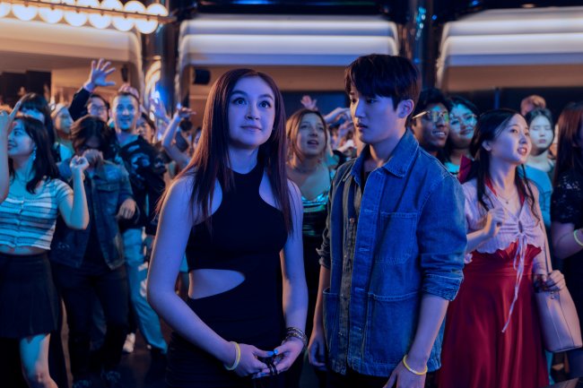 Anna Cathcart como Kitty Song Covey e Choi Min-yeong como Dae em XO, Kitty; eles estão em uma festa iluminados por luzes na cor azul e rodeados por outras pessoas