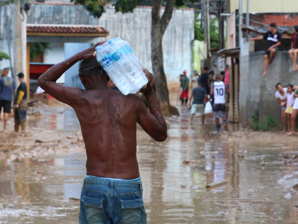 Homem carregando água em meio a tragédia no litoral de SP