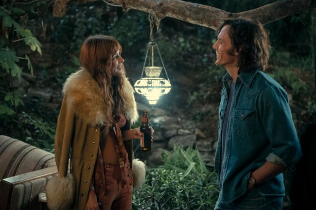 look-casaco-daisy-jones-and-the-six Foto de uma cena da série Daisy Jones and The Six com os personagens Daisy e Billy.