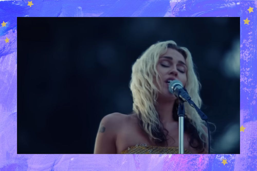 Miley Cyrus cantando de olhos fechados; a margem é uma textura em tons de azul, branco, lilás e roxo com estrelas amarelas como decoração