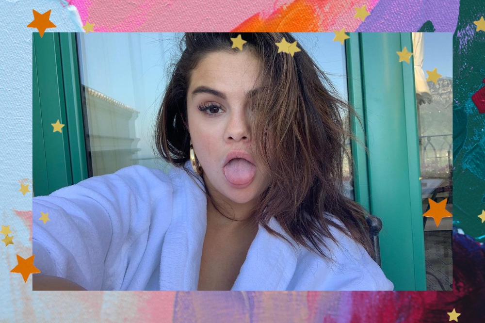 Montagem com o fundo colorido e detalhe de estrelas nas bordas com a foto da Selena Gomez no centro. Na imagem ela está com o cabelo solto, sem maquiagem, usa uma camisa branca. Ela olha para a câmera e mostra a língua.