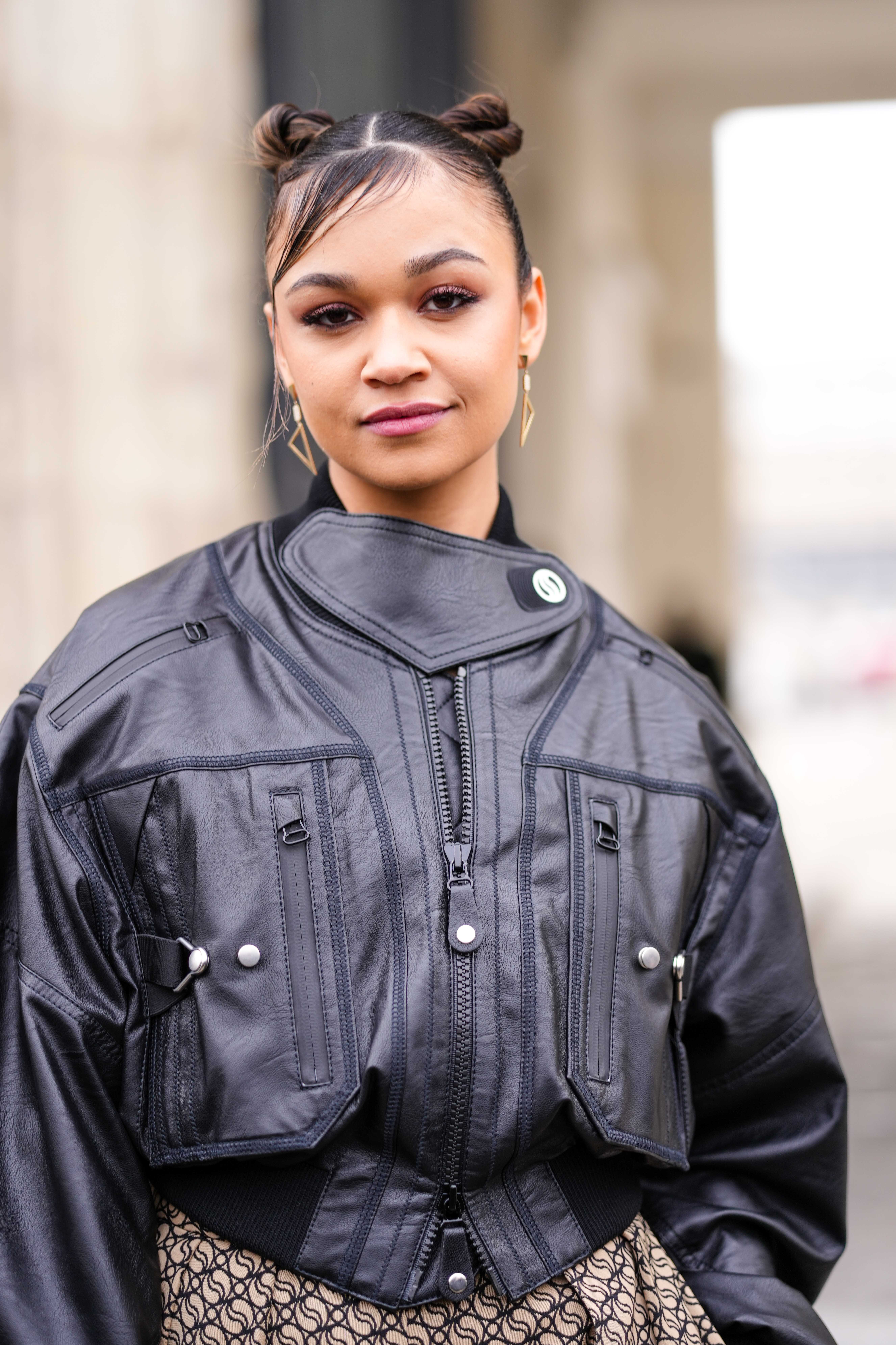 Street Style – Paris Fashion Week – Womenswear Fall Winter 2023 2024 : Day Eight Madison Bailey no desfile da Stella McCartney na semana de moda de Paris usando jaqueta de couro preta, brincos de argola dourados e cabelo preso em dois coques