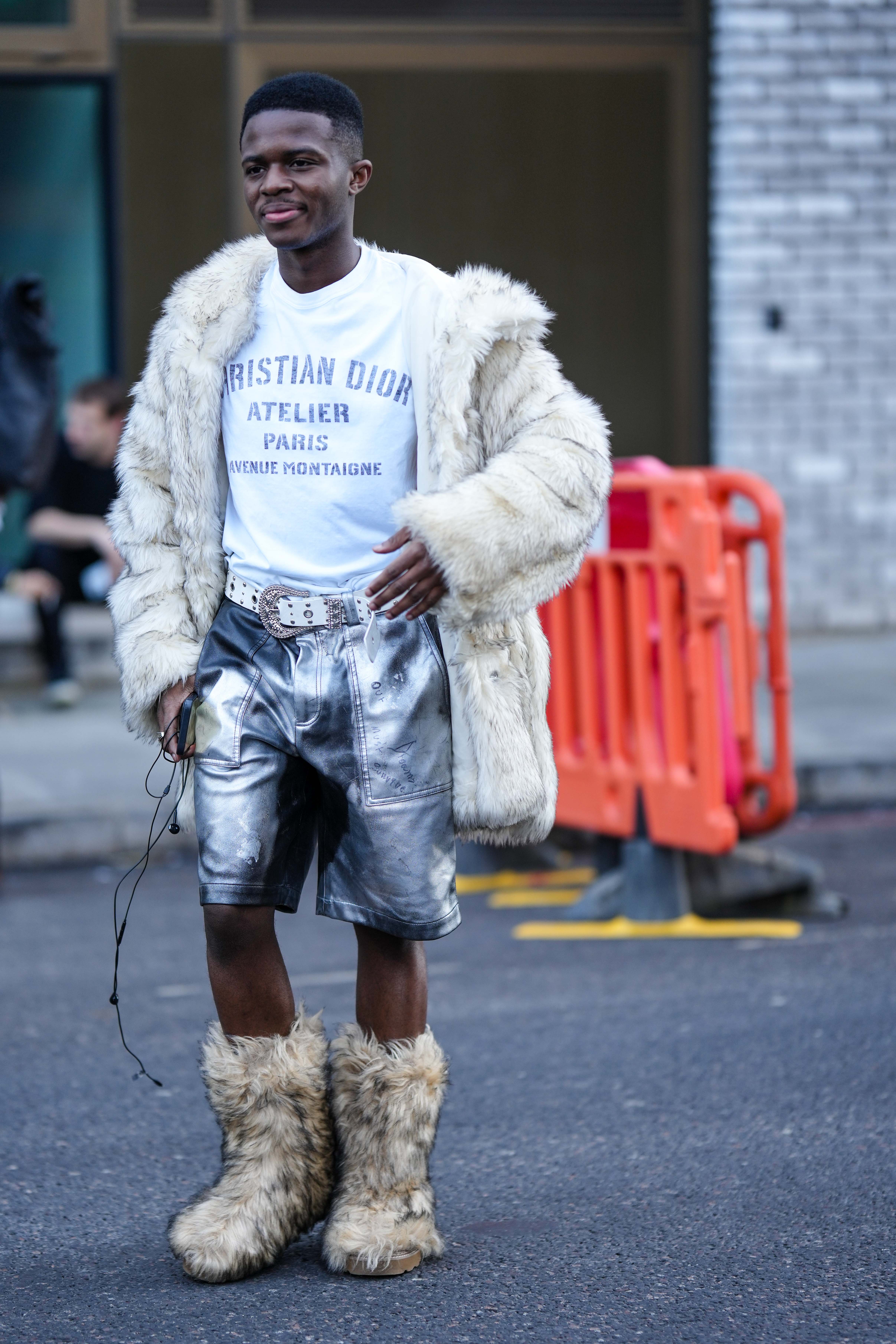 Look com camiseta branca, casaco fofo, bota e bermuda metalizada em prata no street style da semana de moda de Londres