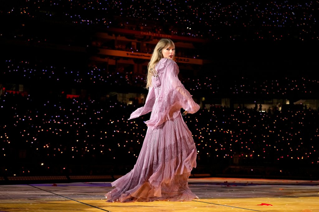 Taylor Swift no primeiro show da The Eras Tour de costas usando vestido longo esvoaçante lilás