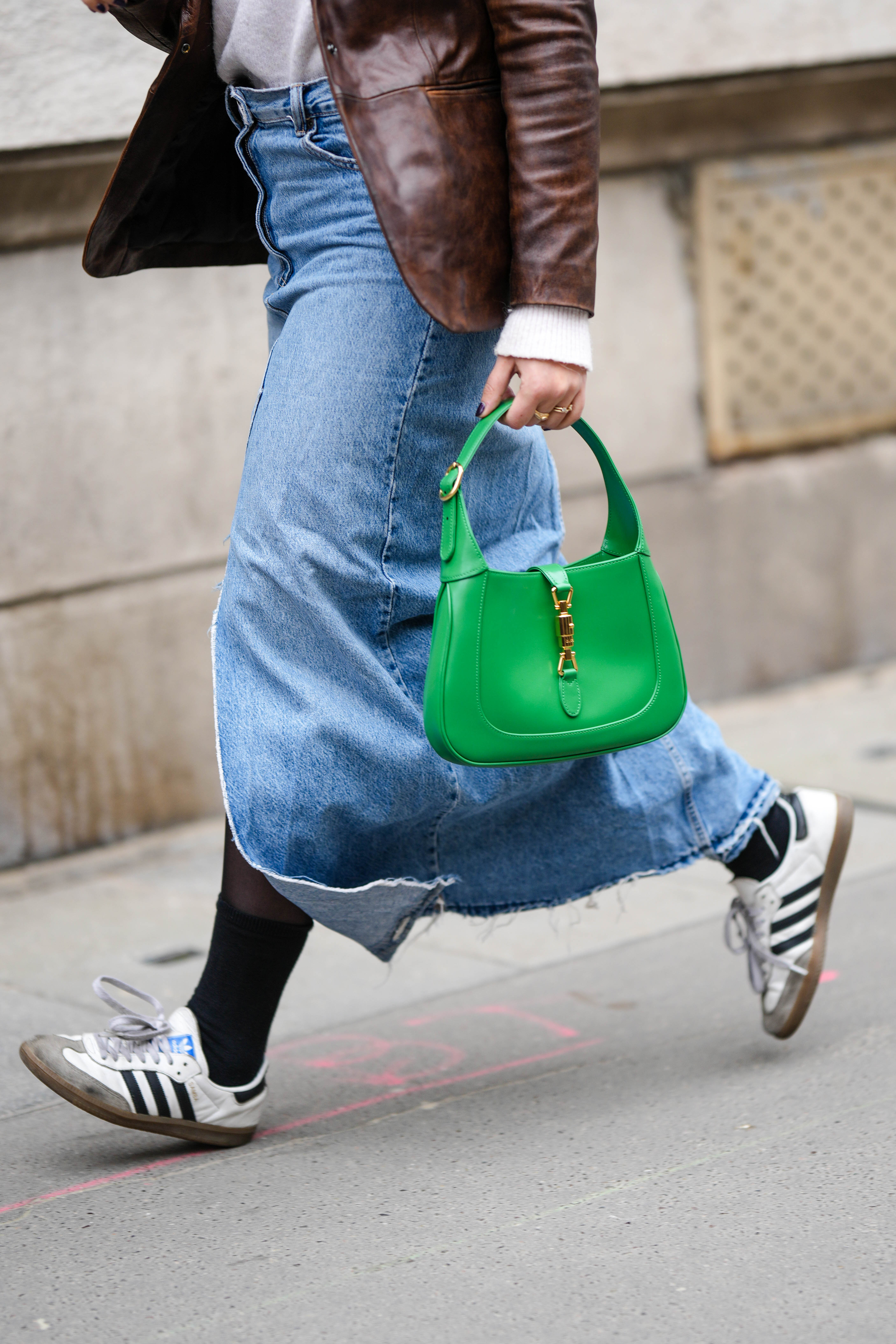 Look com saia jeans, bolsa verde da Gucci e tênis Adidas no street style da semana de moda de Paris em março de 2023
