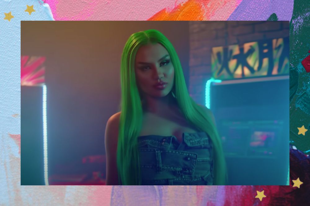 Vivi no clipe de Playground com cabelos verdes e expressão séria; a margem é uma textura nas cores rosa, laranja, lilás, azul, roxo e verde com estrelas amarelas como decoração