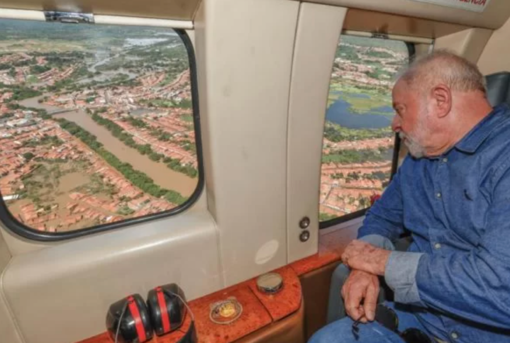 Homem enxerga áreas afetadas pela chuva pela janela do helicóptero