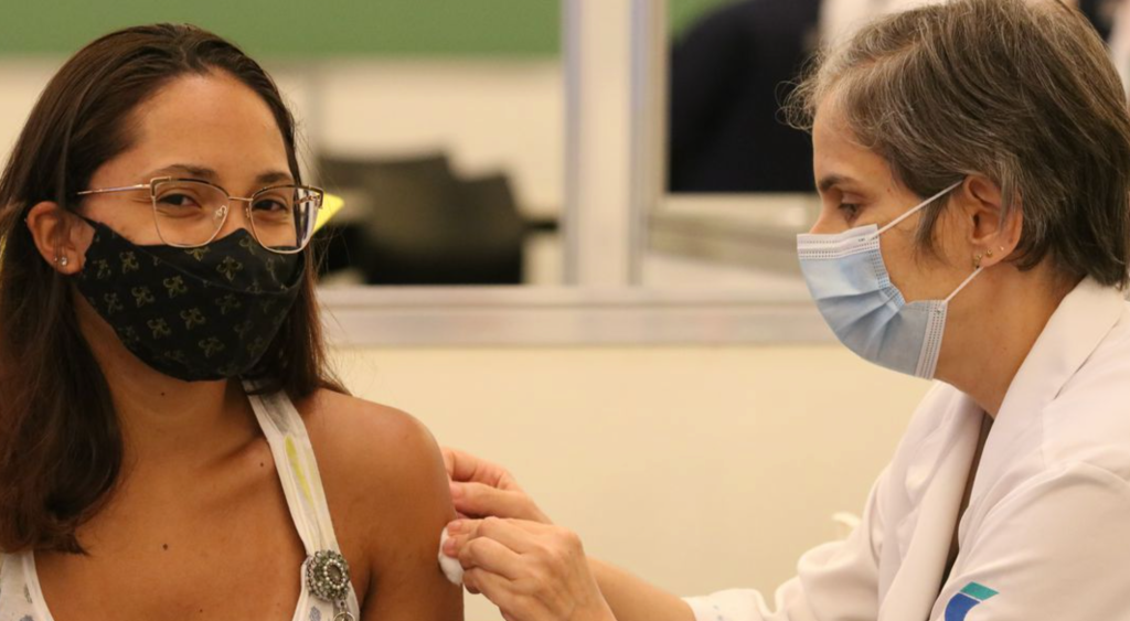 Menina com máscara toma dose de vacina contra covid-19