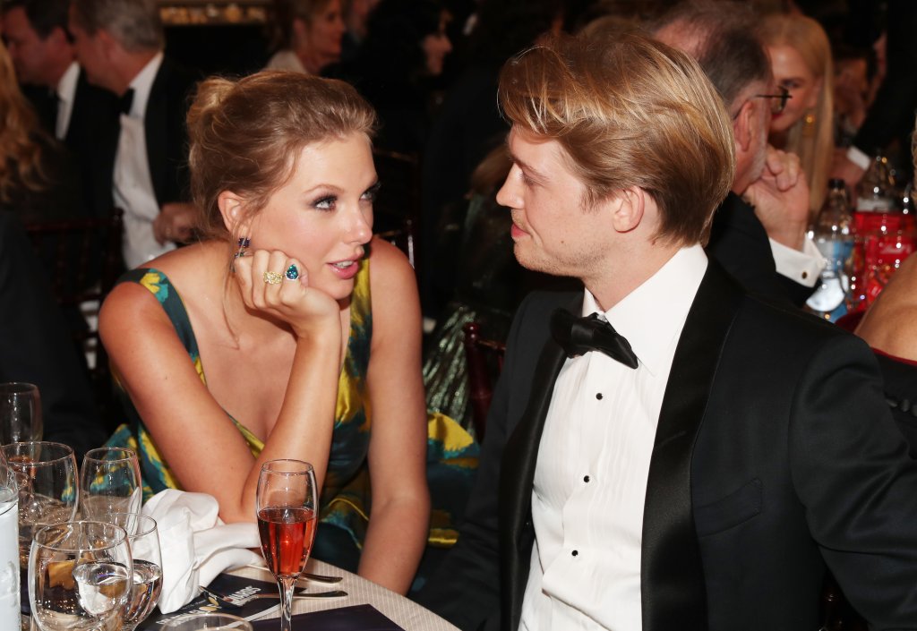 Taylor Swift e Joe no Golden Globe Awards; eles estão sentados se olhando enquanto conversam