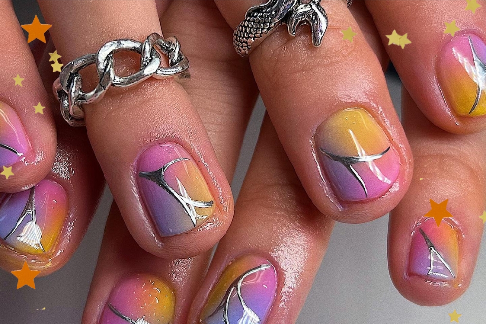 Foto de uma nail art colorida com detalhe de estrelas aplicados na borda.