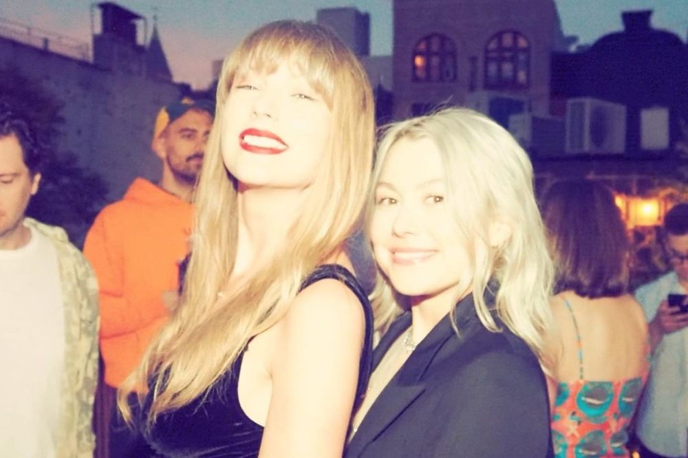 Taylor Swift e Phoebe Bridgers abraçadas e sorrindo para foto em uma área externa