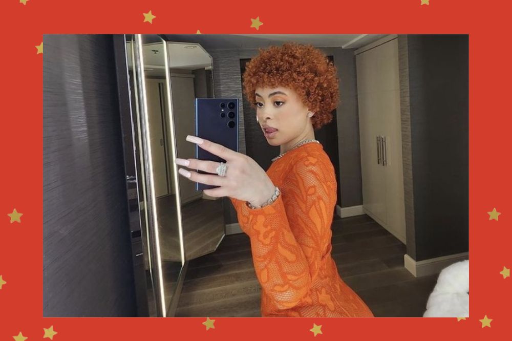 Foto da Ice Spice no espelho vestindo um vestido laranja. Fundo vermelho com estrelas douradas.