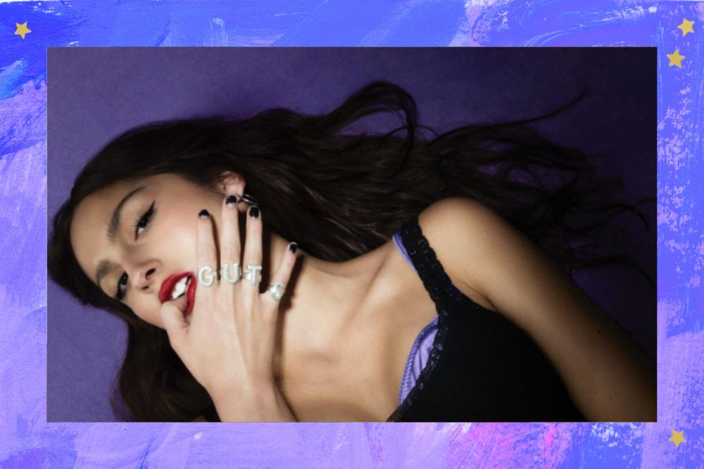 Olivia Rodrigo deitada em fundo lilás em foto publicada em seu Instagram. Fundo em tons de azul e lilás.