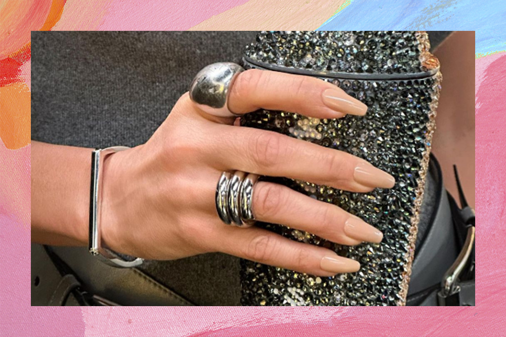 Unhas da Jennifer Lopez pintadas de esmalte nude claro. Montagem em fundo rosa, laranja e azul