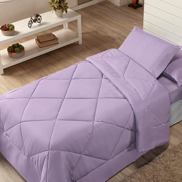Na foto aparece uma cama de solteiro coberta por um edredom lilás. Do lado, aparece uma estante branca com vasos de enfeite em cima