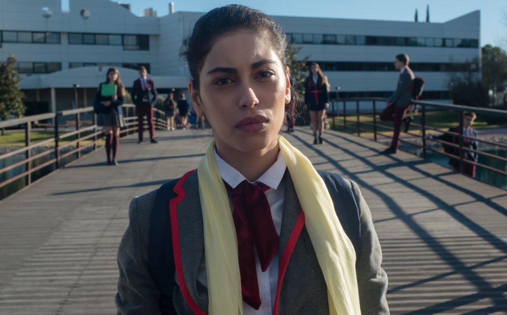 Mina El Hammani como Nadia em cena de Elite; ela está com expressão séria olhando para frente em cena da série