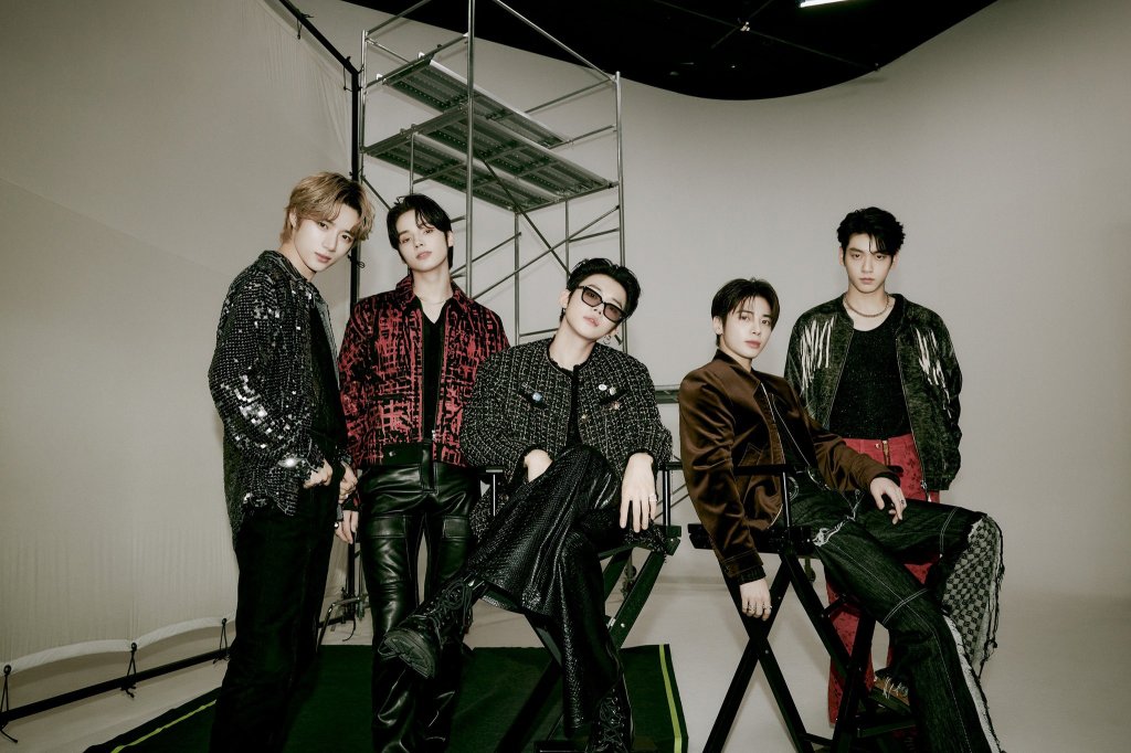 Grupo de k-pop TXT posando para foto com roupas pretas e vermelhas