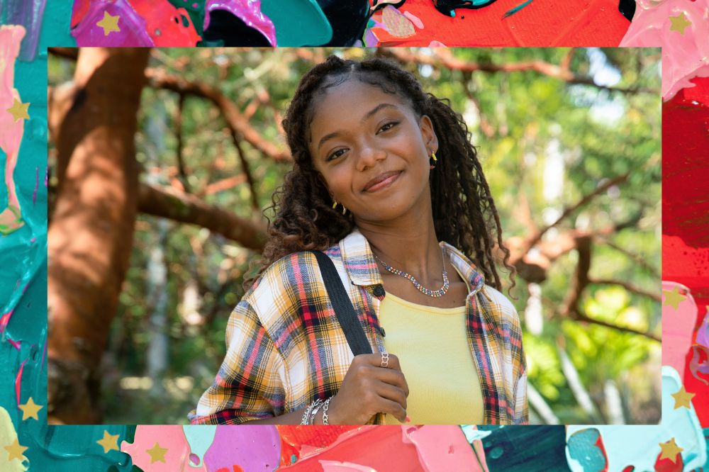 Cecília Chancez posando para foto sorrindo levemente enquanto segura a alça da mochila em um ambiente ensolarado e com árvores; a margem é uma textura nas cores lilás, azul, roxo, verde, rosa, vermelho e preto; estrelas amarelas decoram a imagem