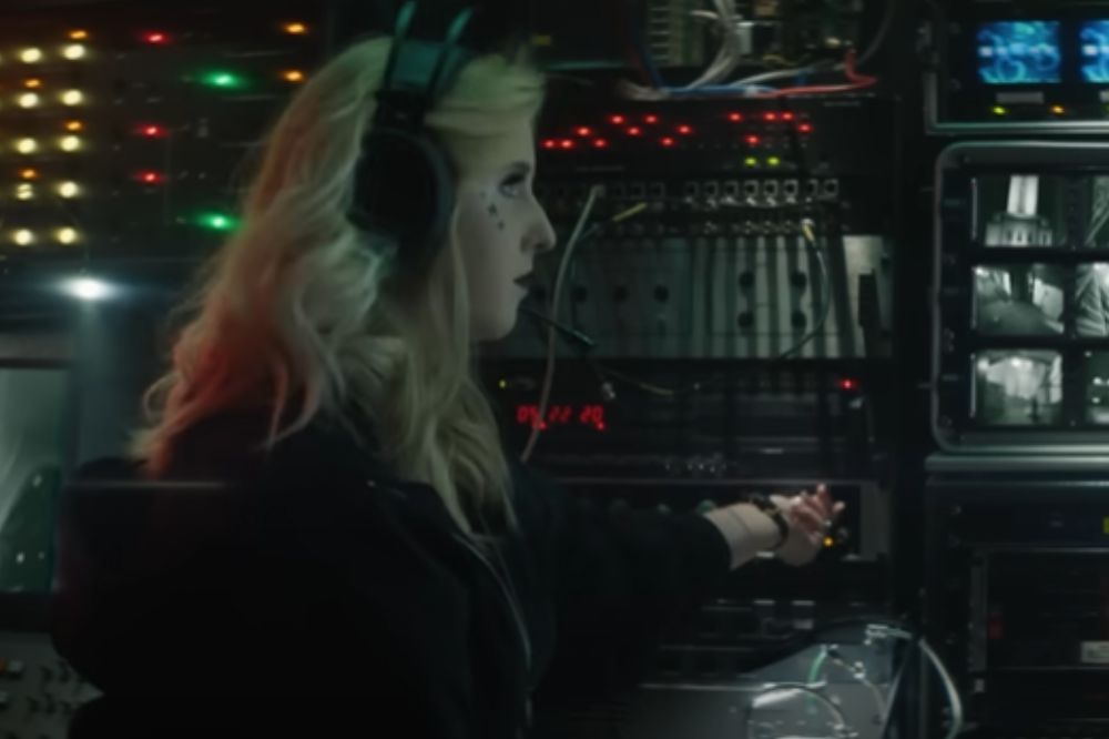 Presley Cash em clipe de I Can See You; ela está mexendo em equipamentos eletrônicos e usa um fone de ouvido com microfone