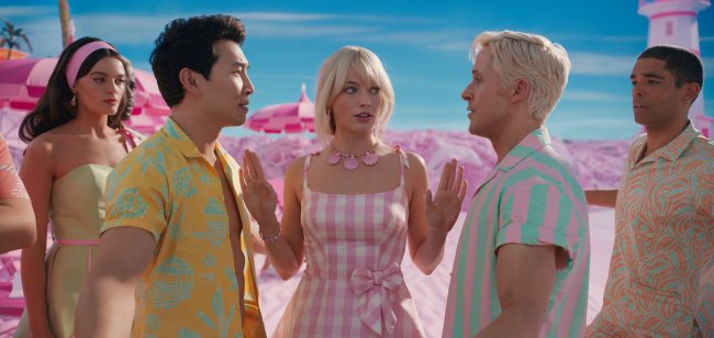 Simu Liu, Margot Robbie e Ryan Gosling em cena de Barbie; Simu e Ryan estão se encarando enquanto Margot está entra os dois com as mãos levantadas