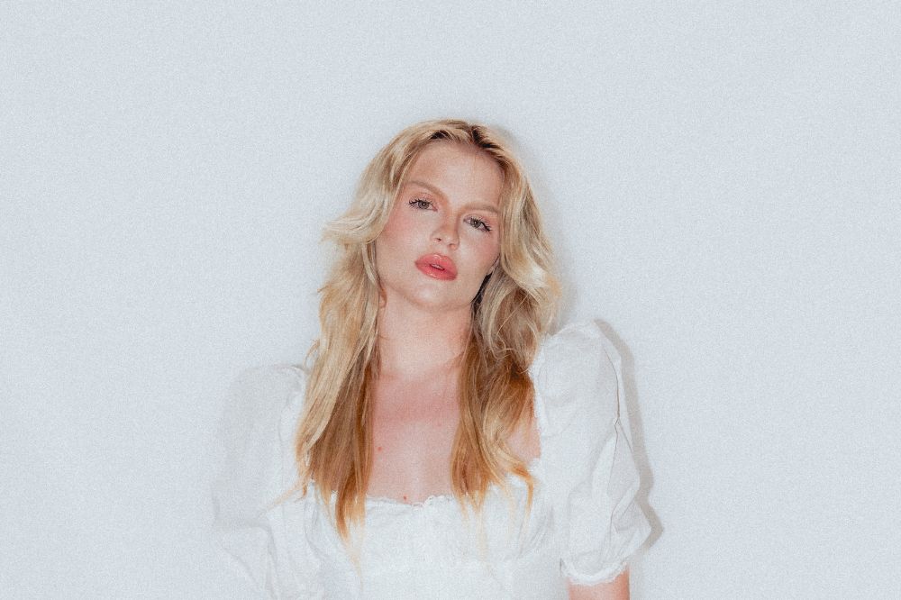 Foto da cantora Luísa Sonza usando roupas brancas em um fundo branco.