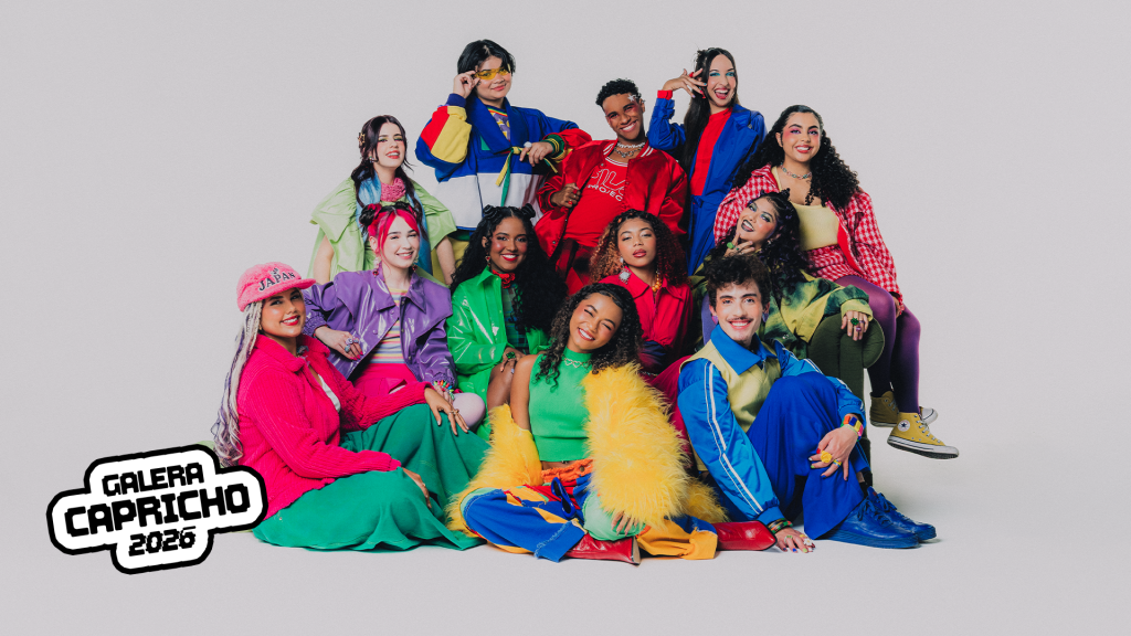 Grupo de 13 jovens, homens e mulheres, de diversas etnias, sorrindo e posando em um fundo branco. Todos vestem roupas coloridas e vibrantes, em tons de verde, azul, vermelho, rosa e amarelo. Alguns estão sentados, outros em pé, formando uma composição dinâmica. No canto inferior esquerdo, o logo GALERA CAPRICHO 2026 em branco e preto.