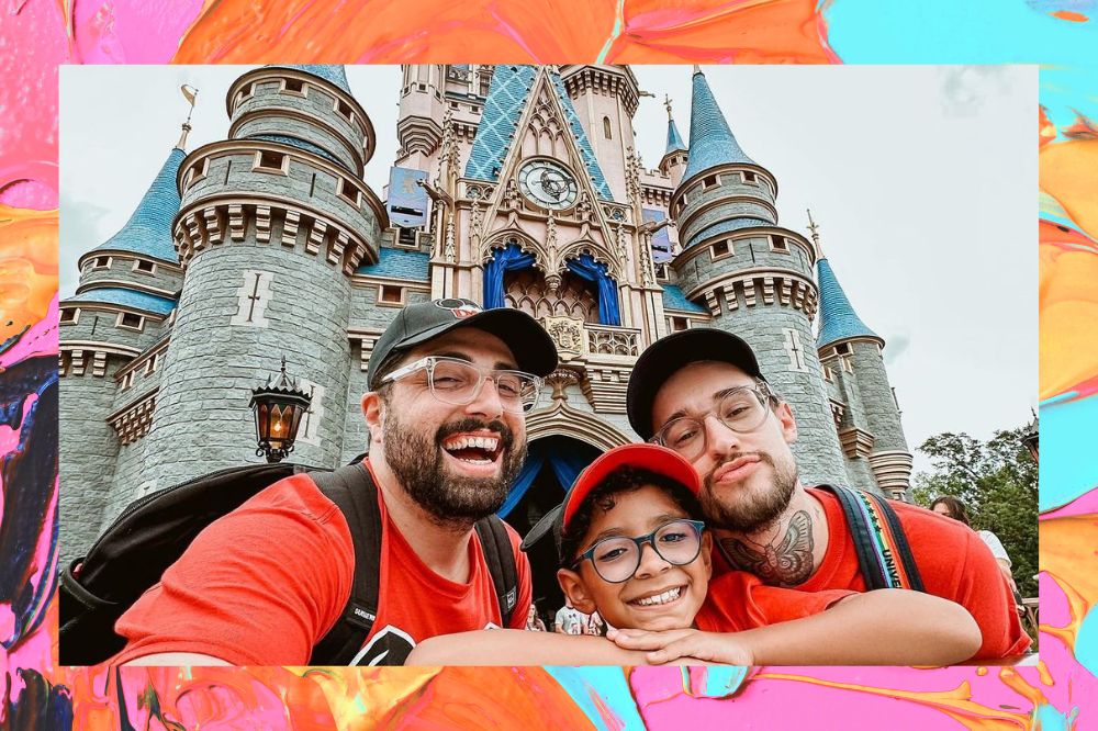 Na foto, tem três pessoas, dois homens e no meio, um garoto. Os três estão usando boné. No fundo, tem castelo da Disney