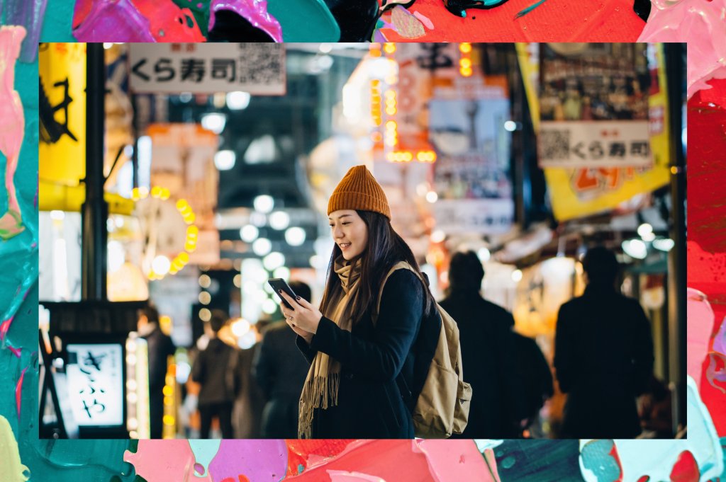Foto de stock de Jovem viajante asiática com mochila em busca de direções com o aplicativo de navegação GPS para smartphone enquanto explora e passeia na movimentada rua do centro da cidade à noite em Osaka, Japão. Estilo de vida e tecnologia. Conceito de viagens e férias