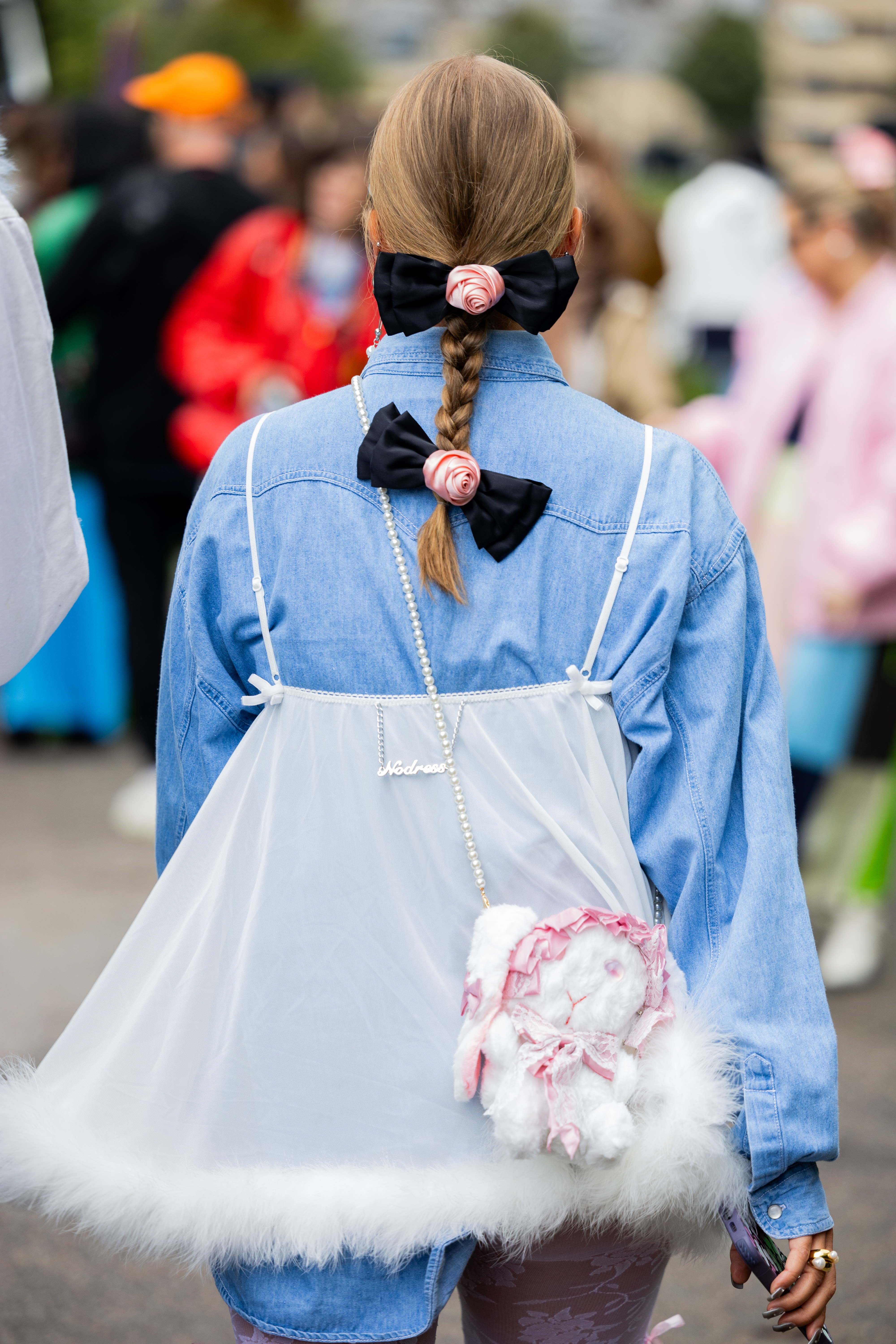Pessoa usando trança no cabelo com laços pretos e flores rosas aplicados na semana de moda de Copenhagen na temporada de primavera-verão 2024