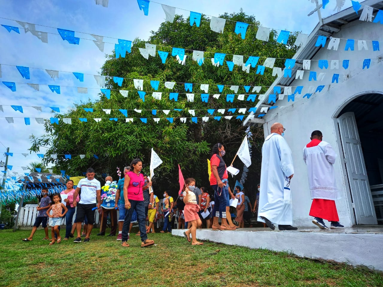 Na imagem, aparecem pessoas entrando em uma capela branca.