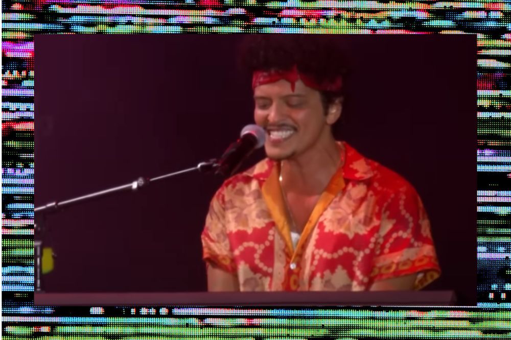 Bruno Mars sorrindo enquanto toca piano em apresentação no The Town; a margem é uma textura de linhas coloridas e fundo preto