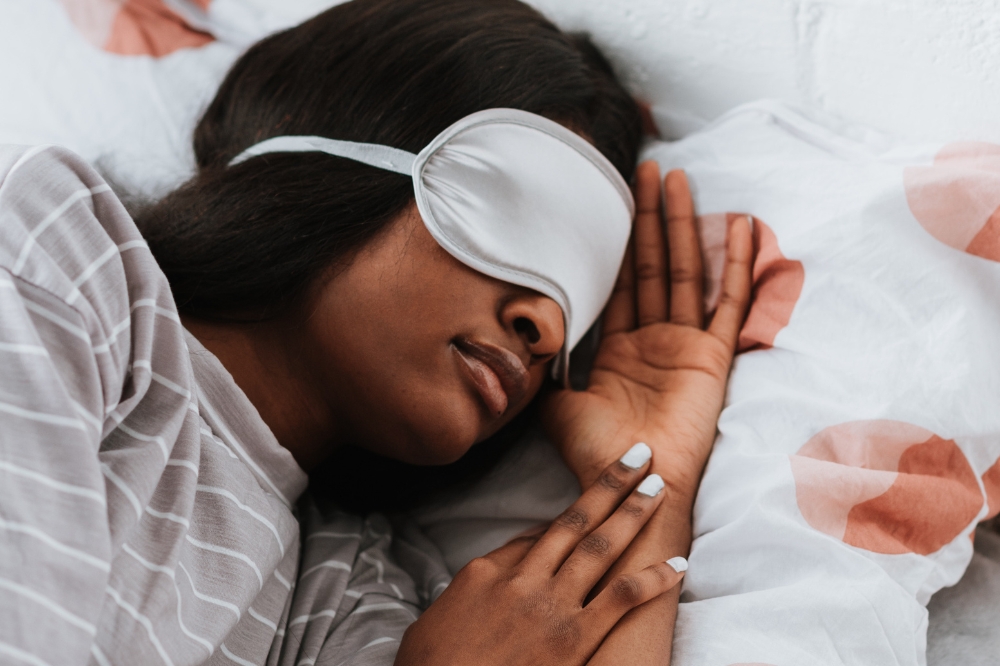 Garota dormindo na cama com máscara facial cobrindo os olhos