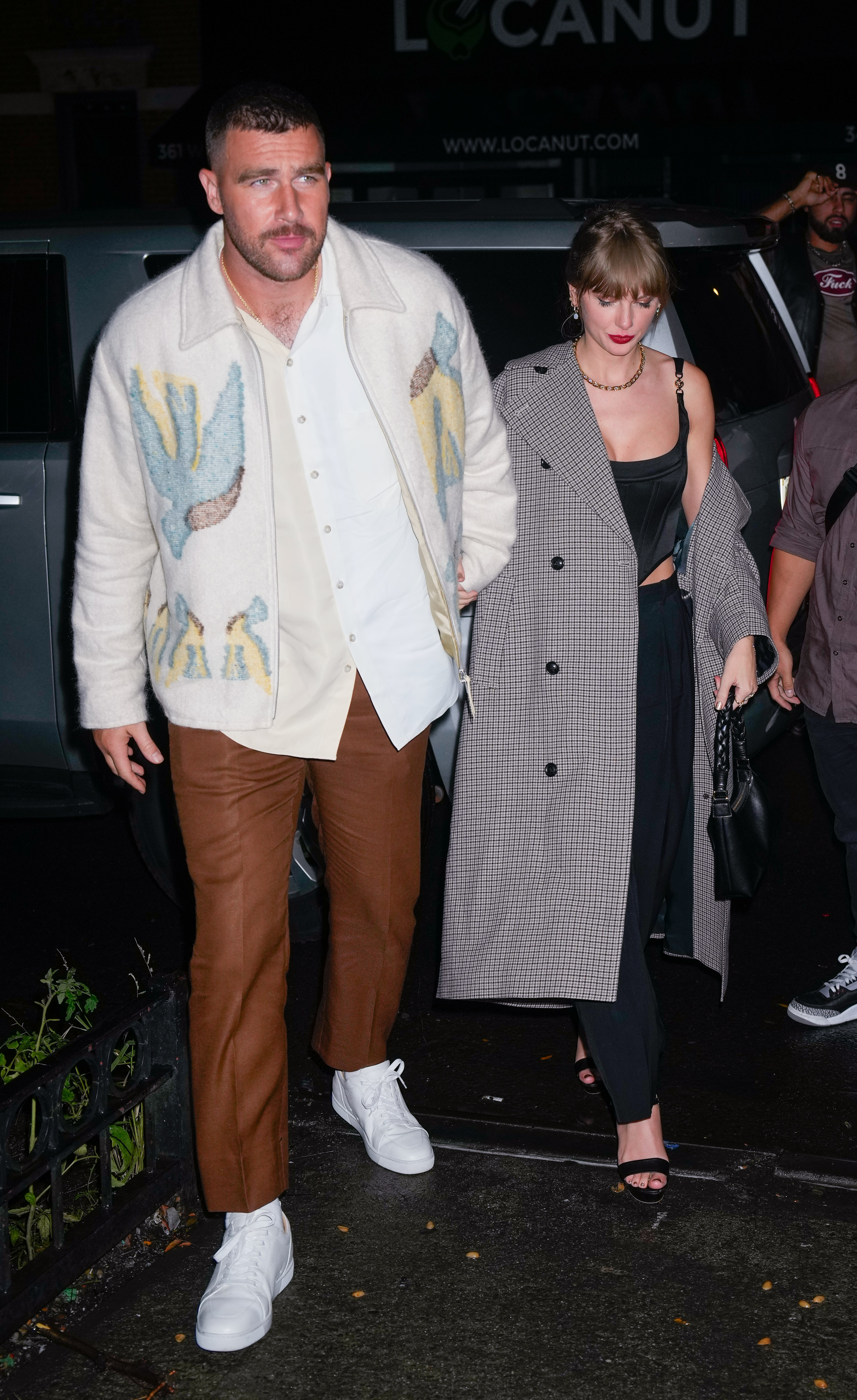 Travis Kelce e Taylor Swift andando de mãos dadas durante a noite em Nova York