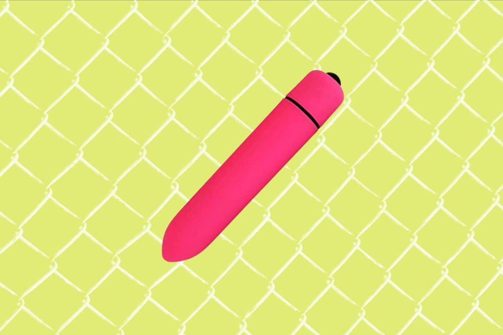 Vibrador bullet pequeno, em formato de uma cápsula, pink. Está em um fundo verde claro