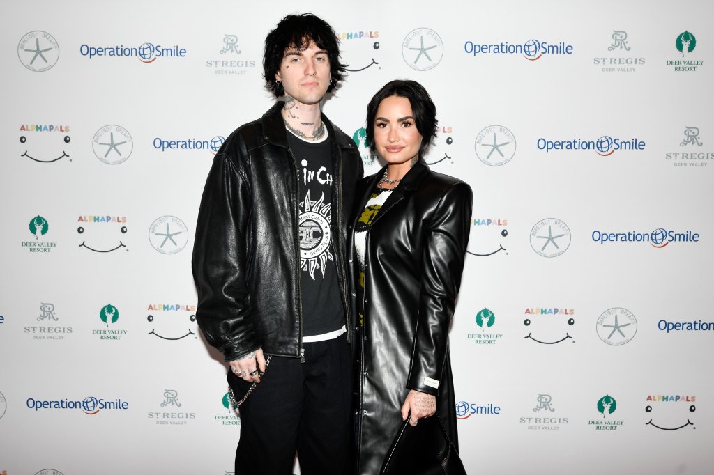 Demi Lovato e Jutes posando para foto juntos; ambos usam roupas pretas e estão com expressões neutras