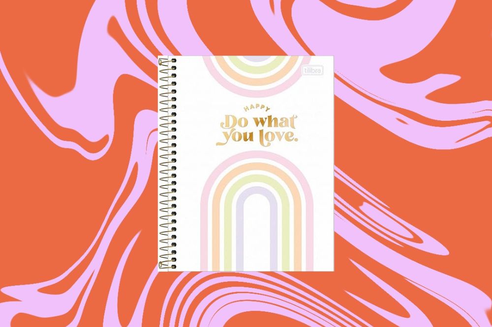 Caderno branco com dois arco-íris desenhados em cores pastéis, na parte inferior e superior, em um fundo laranja e rosa