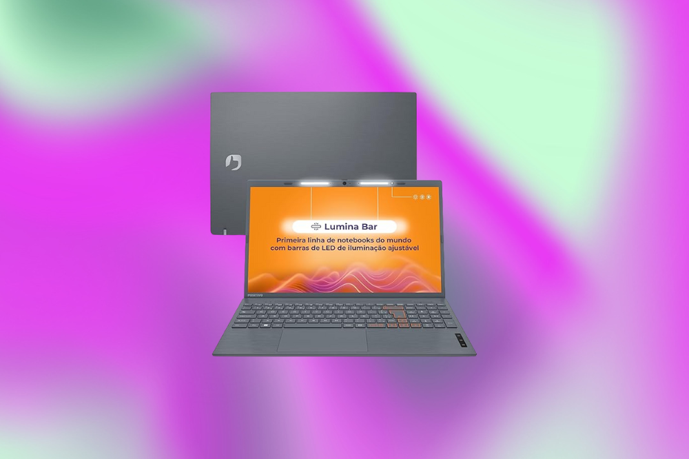 Imagem de um laptop cinza com uma tela laranja em um fundo roxo e verde claro
