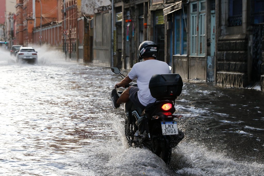 Rua alagada no Rio de Janeiro e uma moto passando pela água