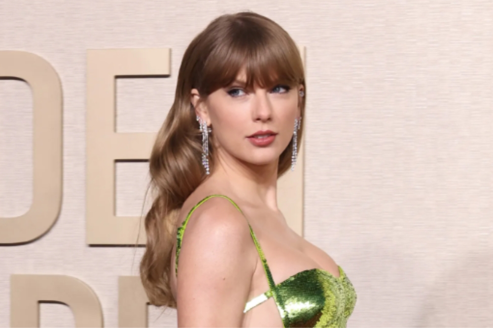 Taylor Swift posando para foto no Globo de Ouro 2024; ela usa um vestido verde e está com expressão neutra olhando para foto de lado por cima do ombro