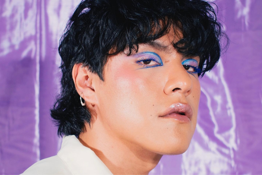 Garoto com expressão facial séria usando delineado azul na maquiagem