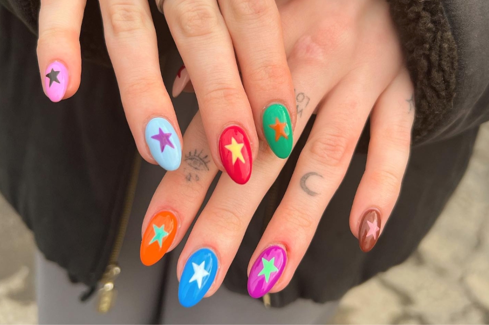 Mãos com esmaltes coloridos nas unhas e desenhos de estrelas