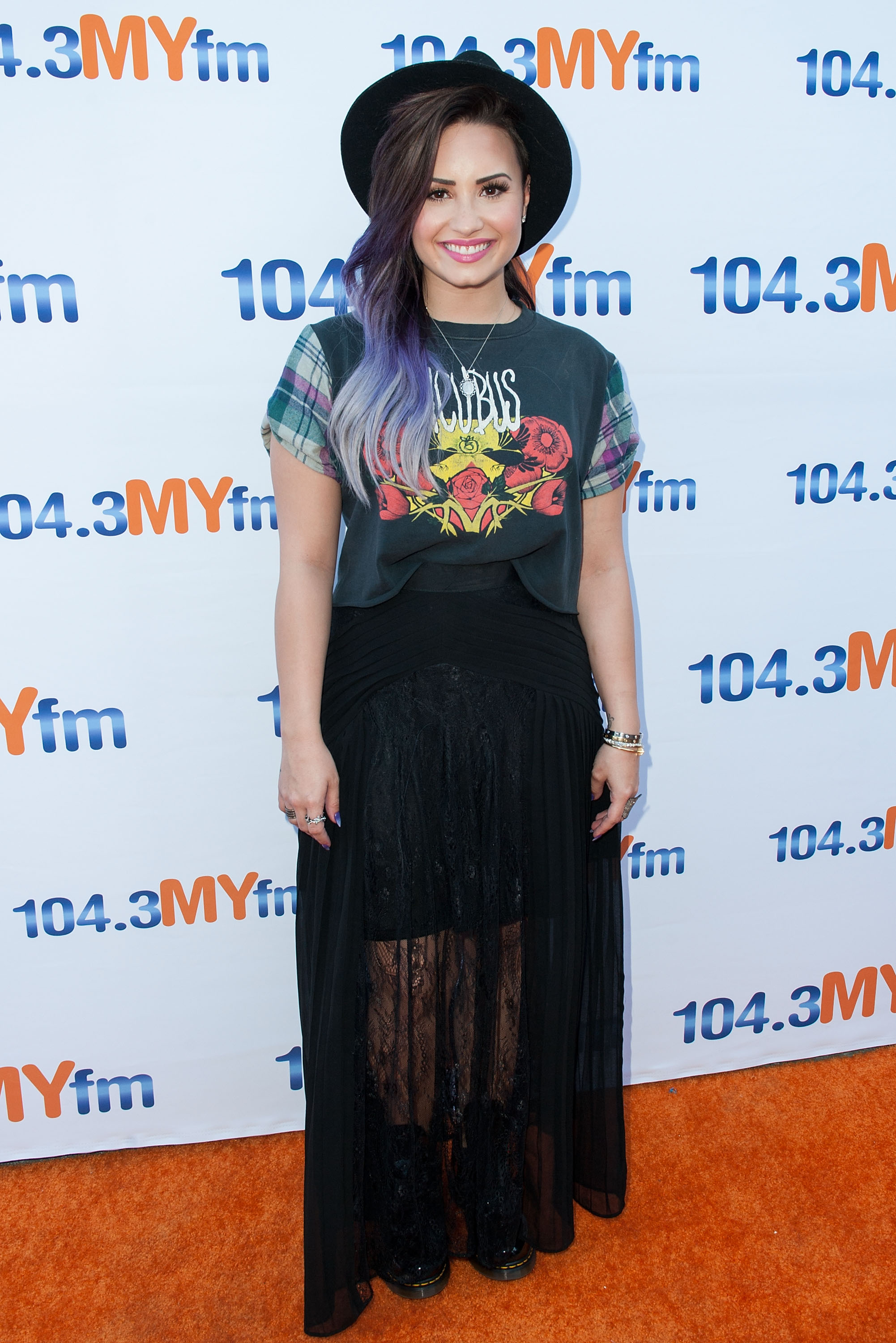 Look da Demi Lovato em 2014 com camiseta, saia preta, coturno e chapéu