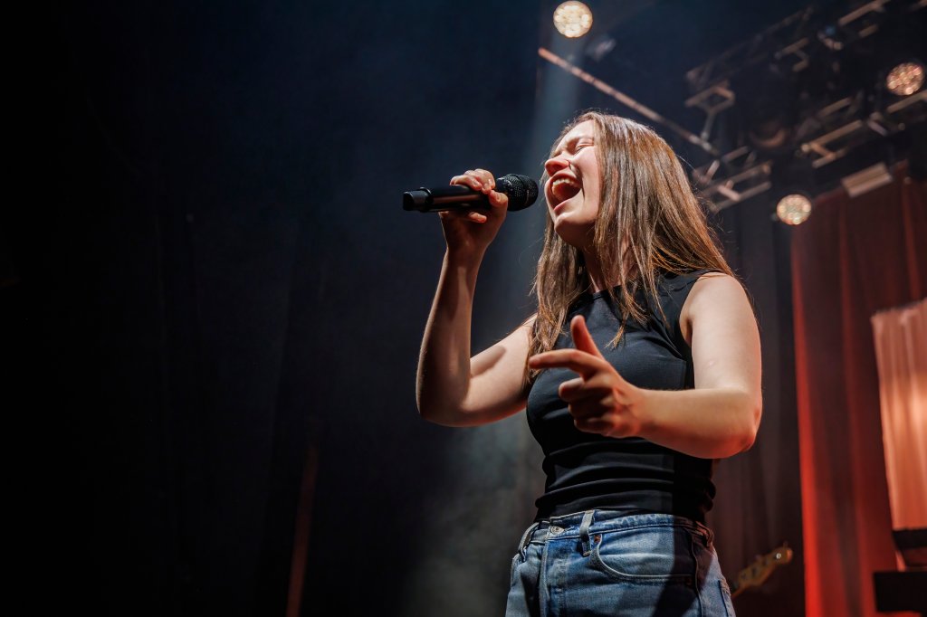 Sigrid se apresentando em Oslo; ela usa cançã jeans com uma regata preta e cabelo solto enquanto canta