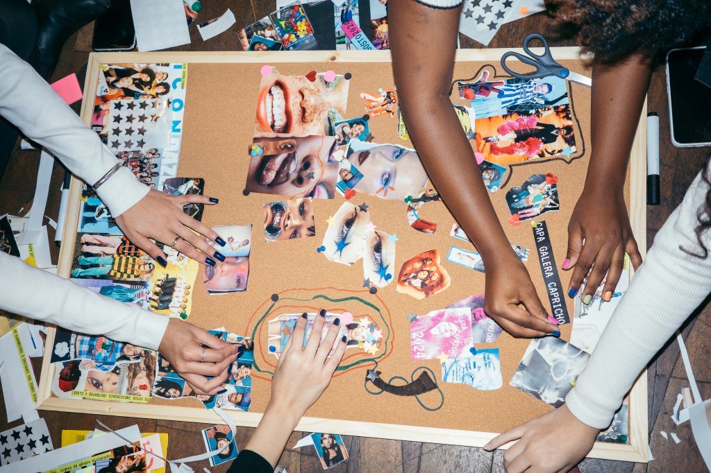 Mãos montando um painel de recortes e fotos